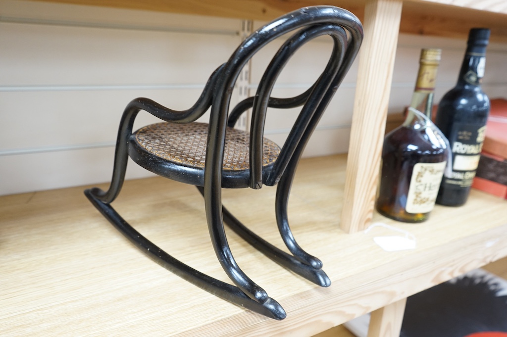 A miniature black bentwood rocking chair with cane seat, possibly made as an apprentice piece, 8cm high at the back, rockers 33cm long. Condition - some scuffing to frame, seat good.